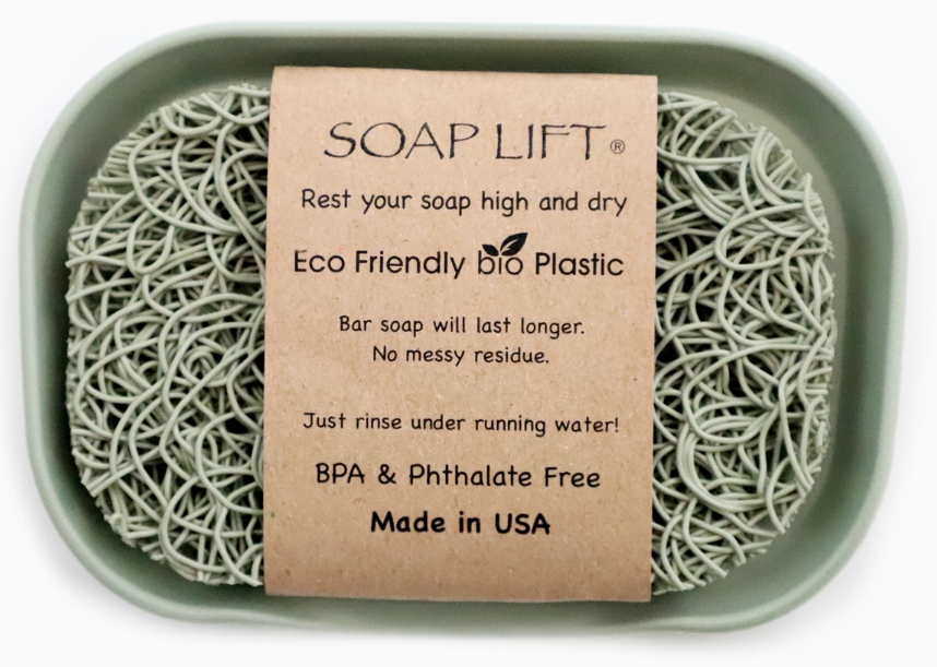 A soap lift made from eco-friendly bio plastic placed inside a green dish, featuring a label that explains its benefits for keeping soap dry and lasting longer, bpa & phthalate free, and made in the usa.