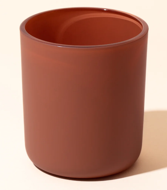 A simple terracotta-colored vessel with smooth walls and a minimalist design.